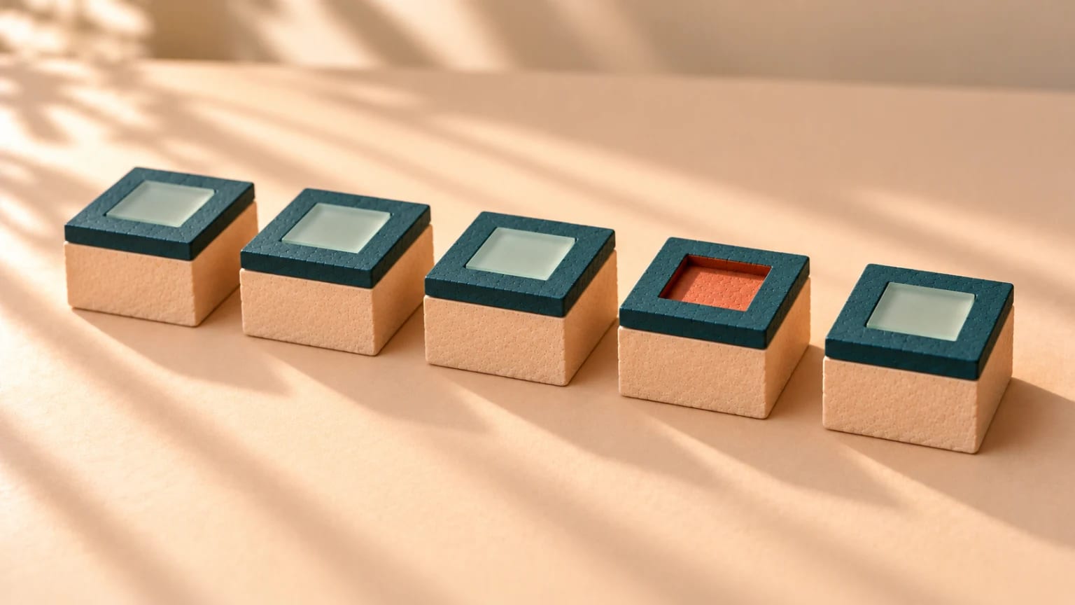 Five clay blocks in a row, four of them holding a frosted glass tile seated flush into the top; the fourth block’s recess is empty, its bare coral floor showing.